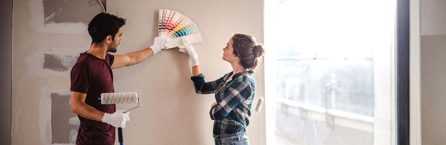 Young couple reviewing paint swatches before painting a wall in their house