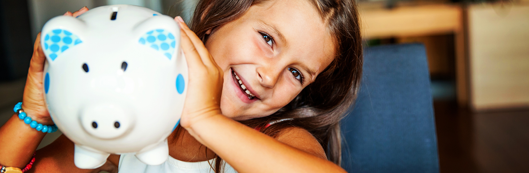 Smiling girl holding white piggy bank