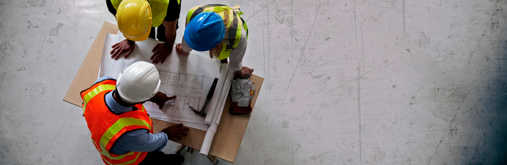 Three architects wearing hard hats looking at renderings