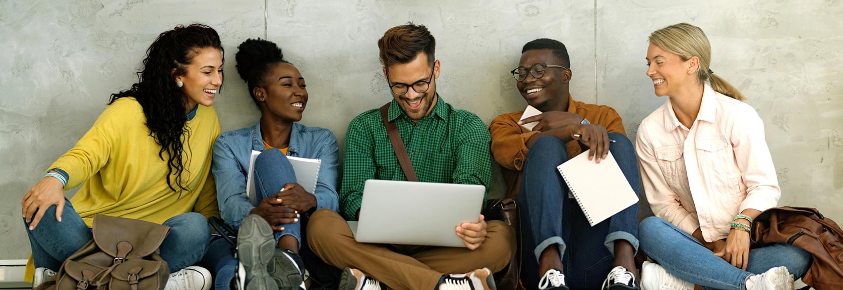 Small group of happy students talking with laptops